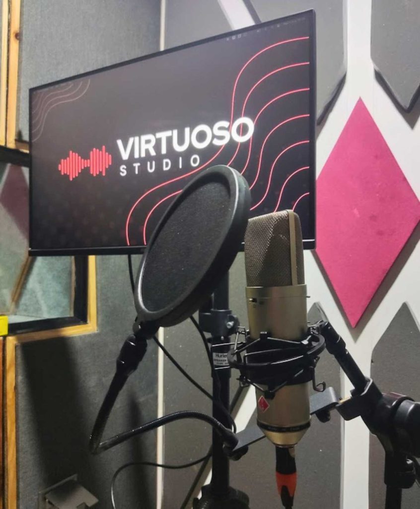 Ruang dubbing Virtuoso Studio dengan mikrofon kondensor profesional, pop filter, dan layar monitor untuk sinkronisasi suara karakter anime.