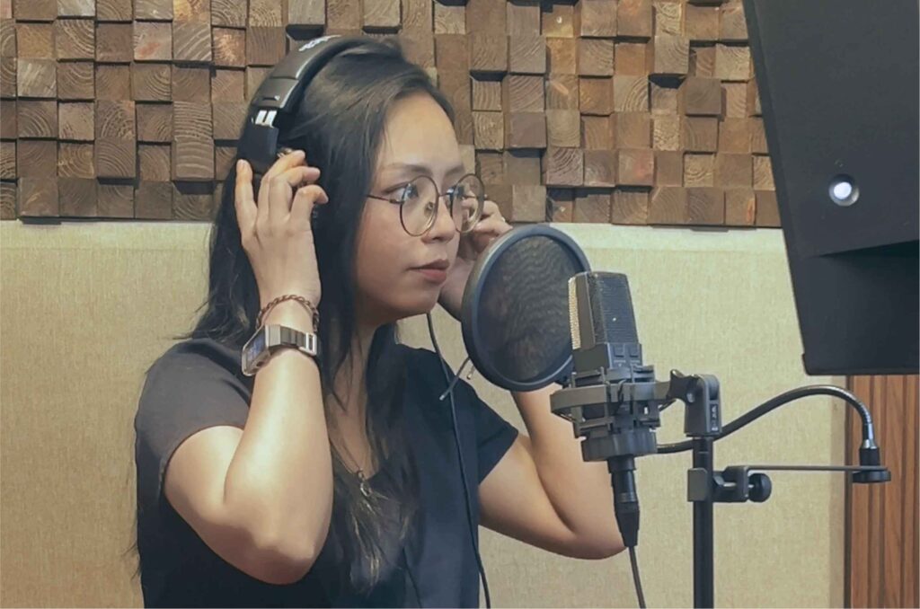Female voice actor recording Indonesian dubbing in a professional recording studio.