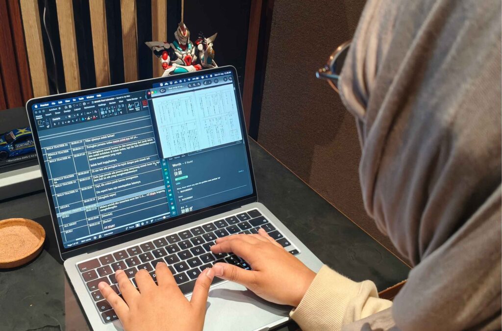 Translator working on localization and adaptation documents on a laptop.